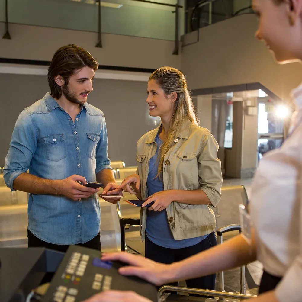 A male barista smiles at the camera while making a coffee
