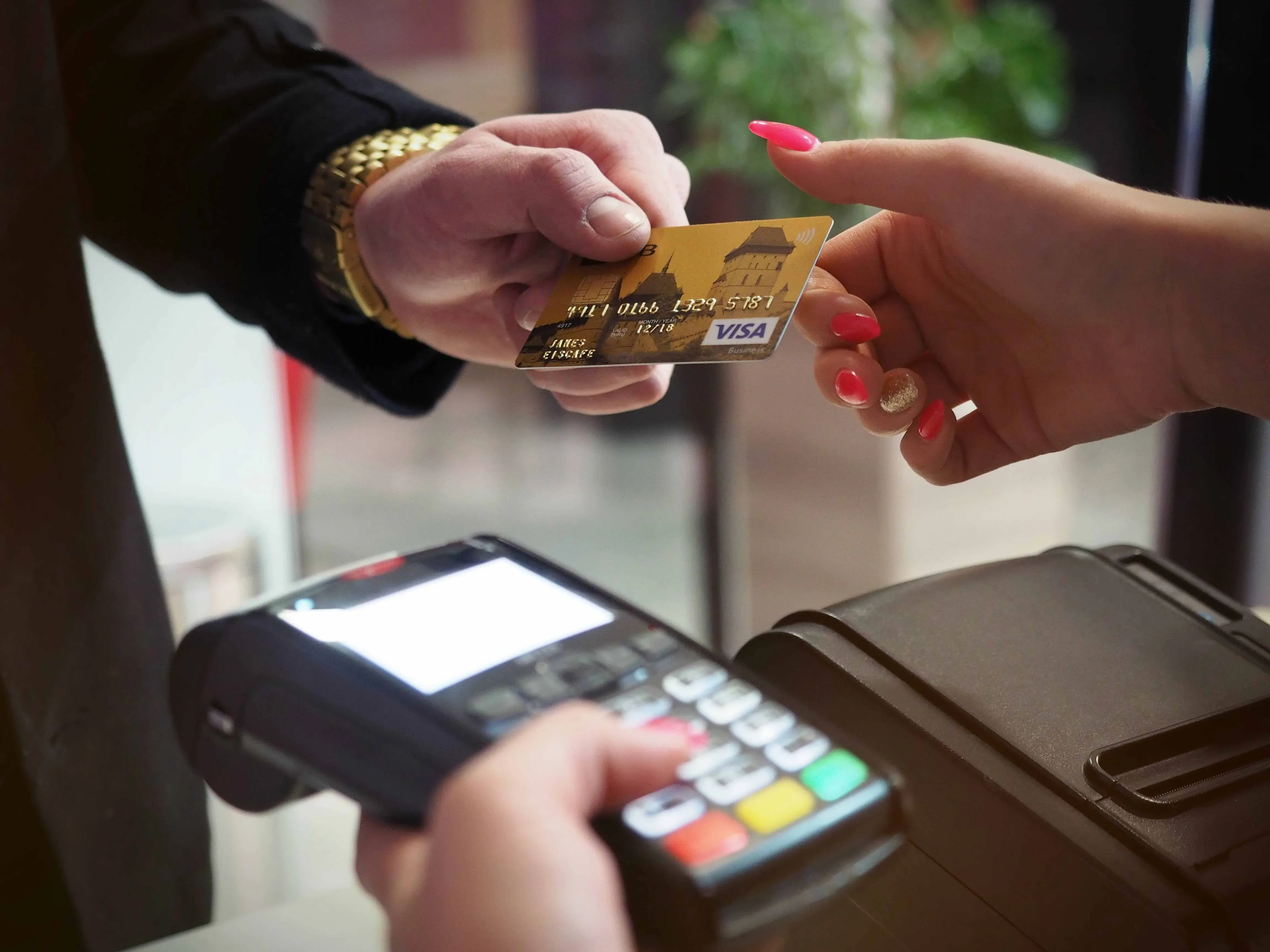 A credit card being handed to a member of hospitality staff for payment