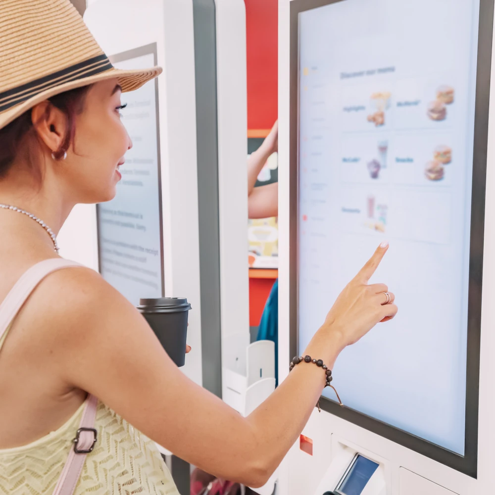 A woman using a self-ordering kiosk in a fast food restaurant